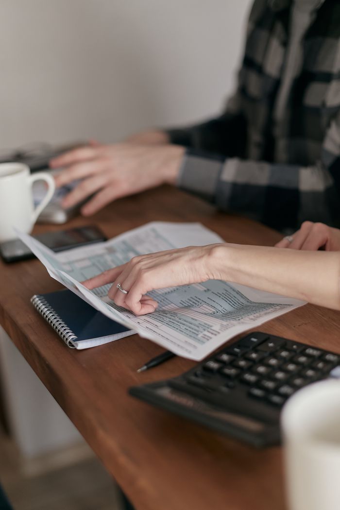 Teamwork at a desk with calculator, documents, and hands interacting over financial papers.